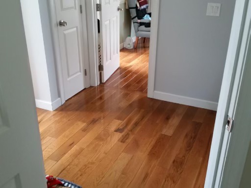 turman-hardwood-flooring-hallway-corridor-warm-medium-tone Natural Red Oak hardwood flooring installation in a bedroom with a ceiling fan and light wood furniture.
