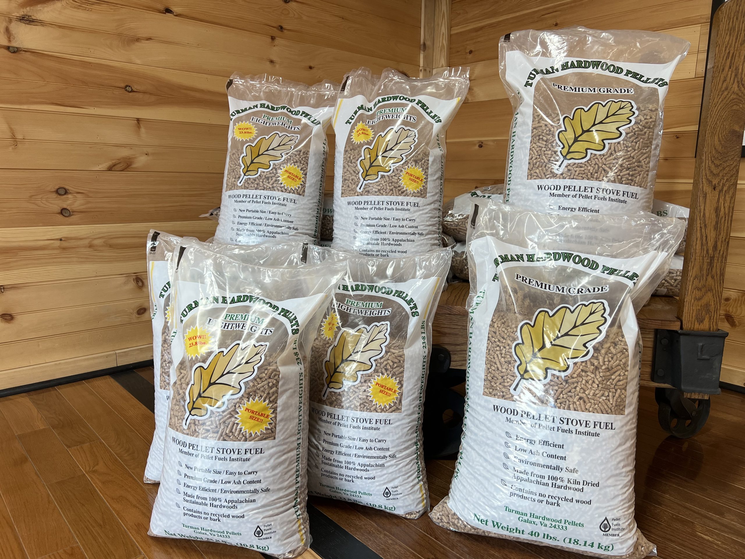 Bags of Turman Hardwood Pellets stacked in a wood-paneled room, showing premium-grade Appalachian hardwood stove fuel made in Virginia.
