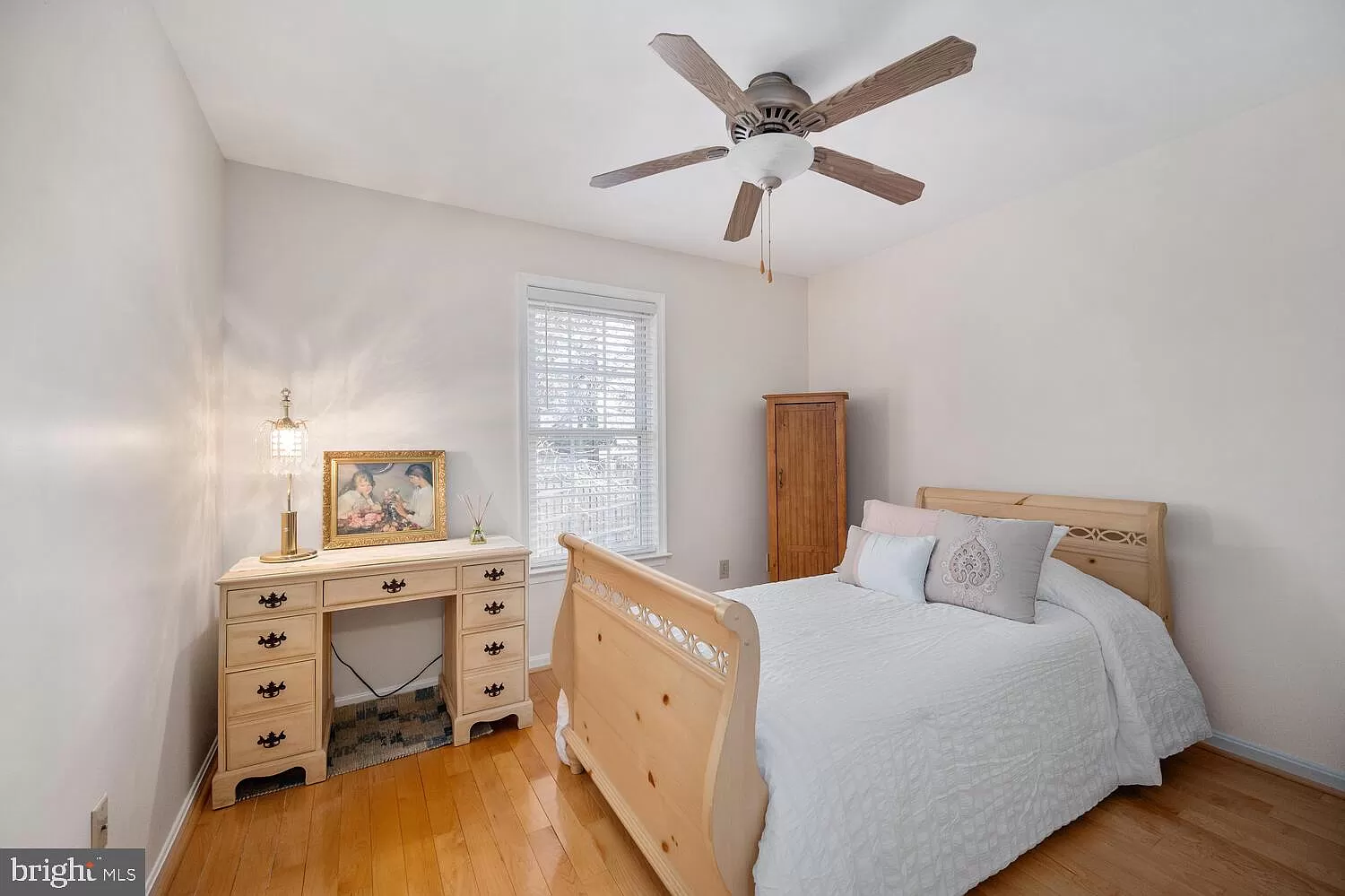 A bright bedroom featuring Turman Hardwood Flooring's Virginia-grown Appalachian hardwood floor with natural grain, shown with light wood furniture and a ceiling fan.