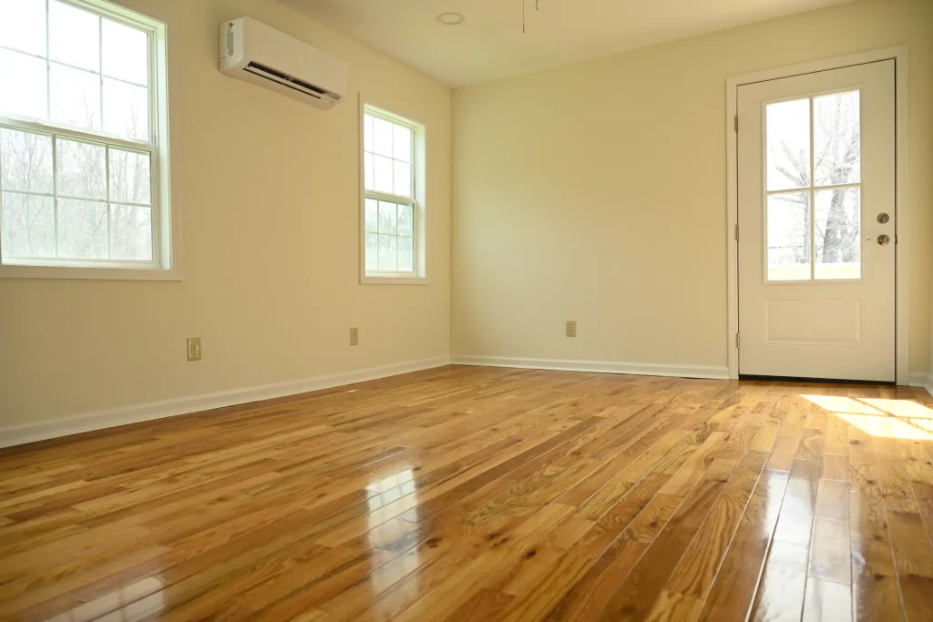 Character Golden Oak Red Oak flooring in a sunlit bedroom with white trim and a glass-paneled door.