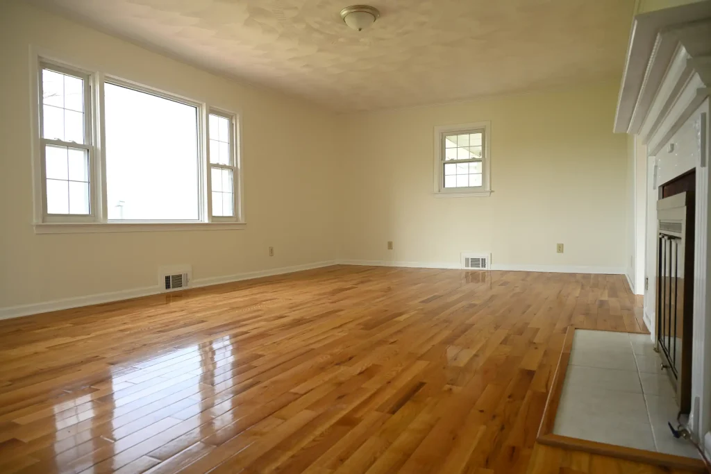 Character Golden Oak Red Oak flooring in a bright living room with a white fireplace and large windows.
