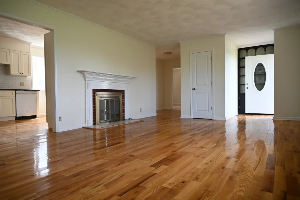 Character Golden Oak Red Oak flooring in a living room and entryway with a brick fireplace and white trim.